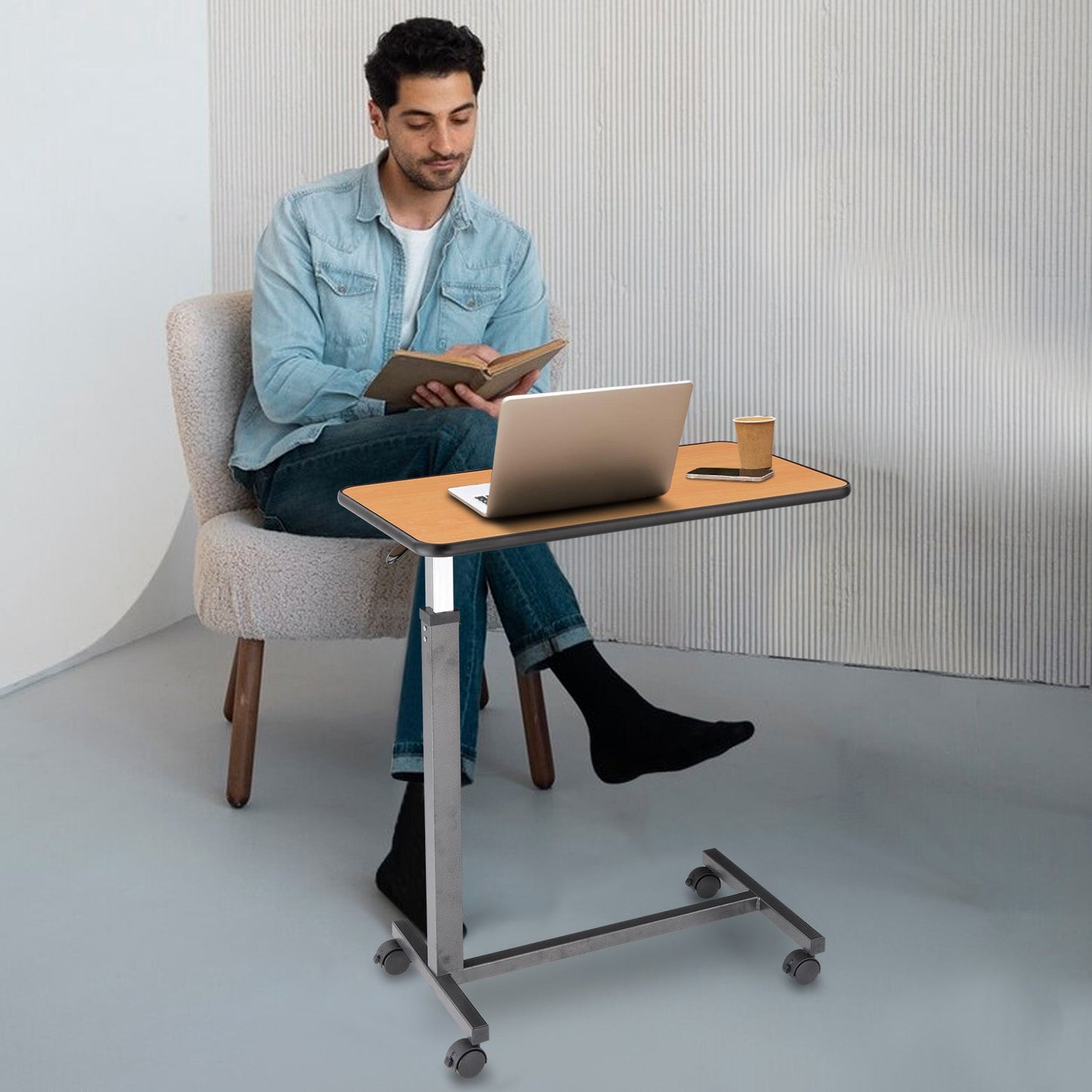 Usage for Work and Study: A young man using the overbed table for reading and working on a laptop, illustrating its versatility in a home office setting.