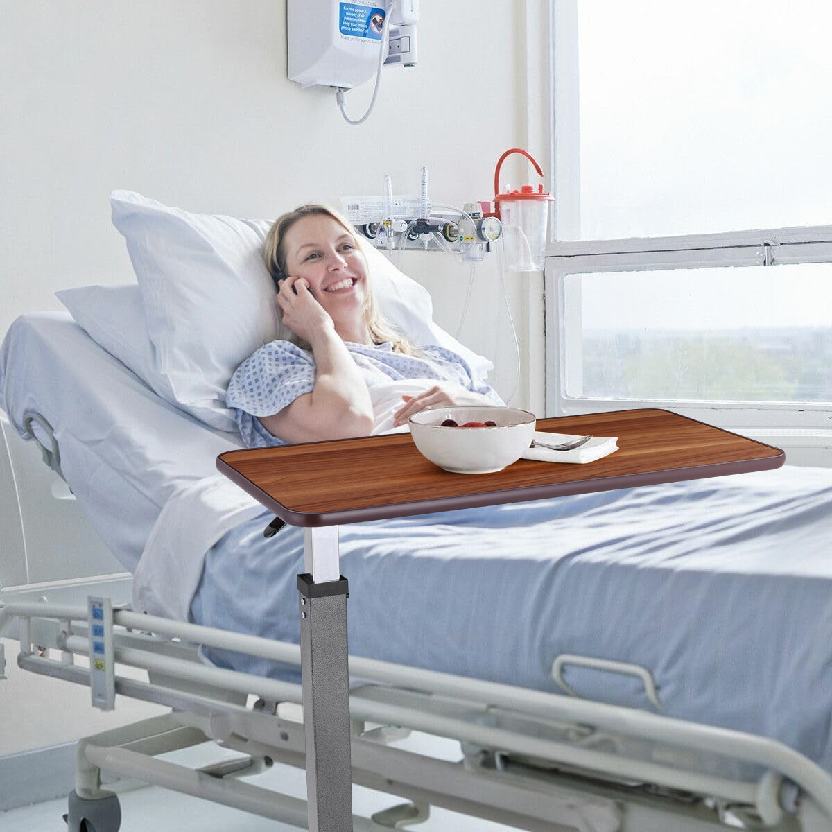 Usage in a Hospital Bed:The overbed table is an essential tool for enhancing the comfort and convenience of patients during recovery. In this scene, a young woman lies in her hospital bed, utilizing the table to enjoy a healthy meal.