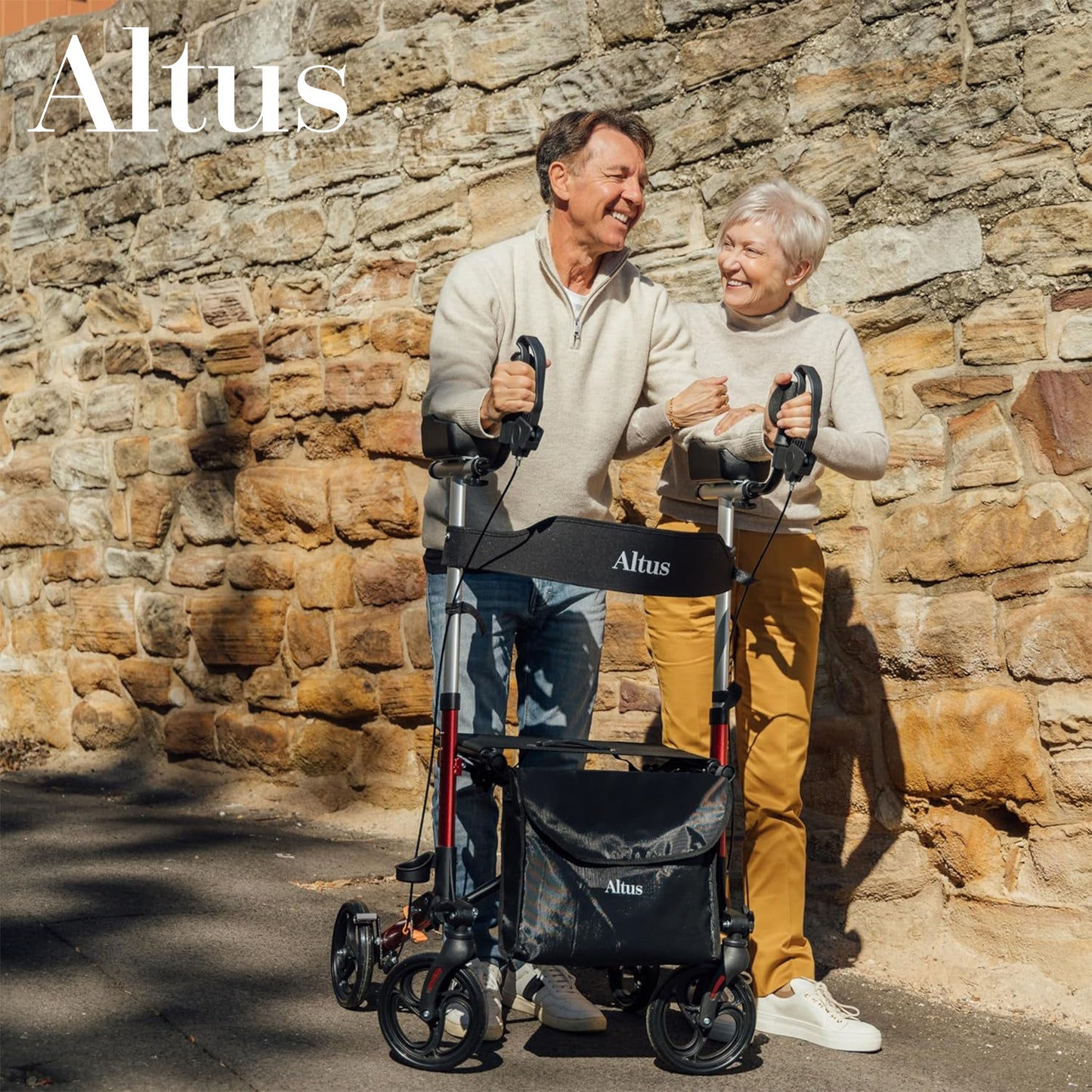 Two people standing with Altus rollators against a stone wall.