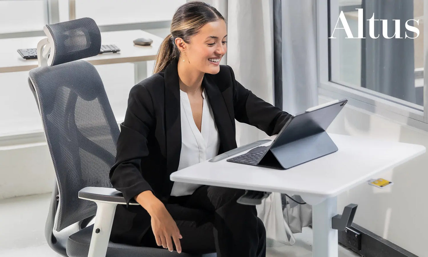 Professional woman using the Altus Premium Sit-Stand Desk in a modern office, working on a tablet.