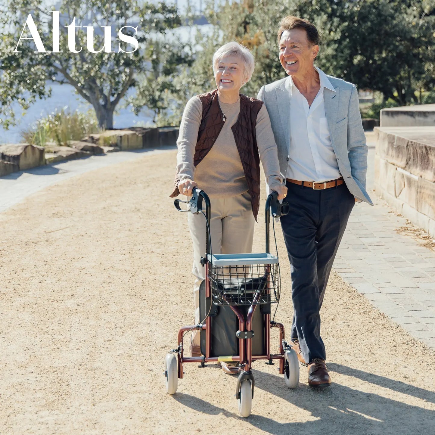 A senior couple enjoying a walk with the Altus Rolling Walker Mobility Aid Rollator in Burgundy Red. The rollator's lightweight design and spacious storage options make it perfect for enhancing mobility and independence for active seniors.