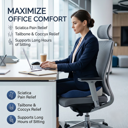 A woman in a navy blazer sits in a gray ergonomic office chair at a desk, working on a laptop in a bright modern office. Text on the image highlights sciatica and tailbone pain relief benefits.