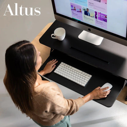 Overhead view of a black sit-to-stand desk converter with a desktop computer, highlighting ergonomic design and desk space.