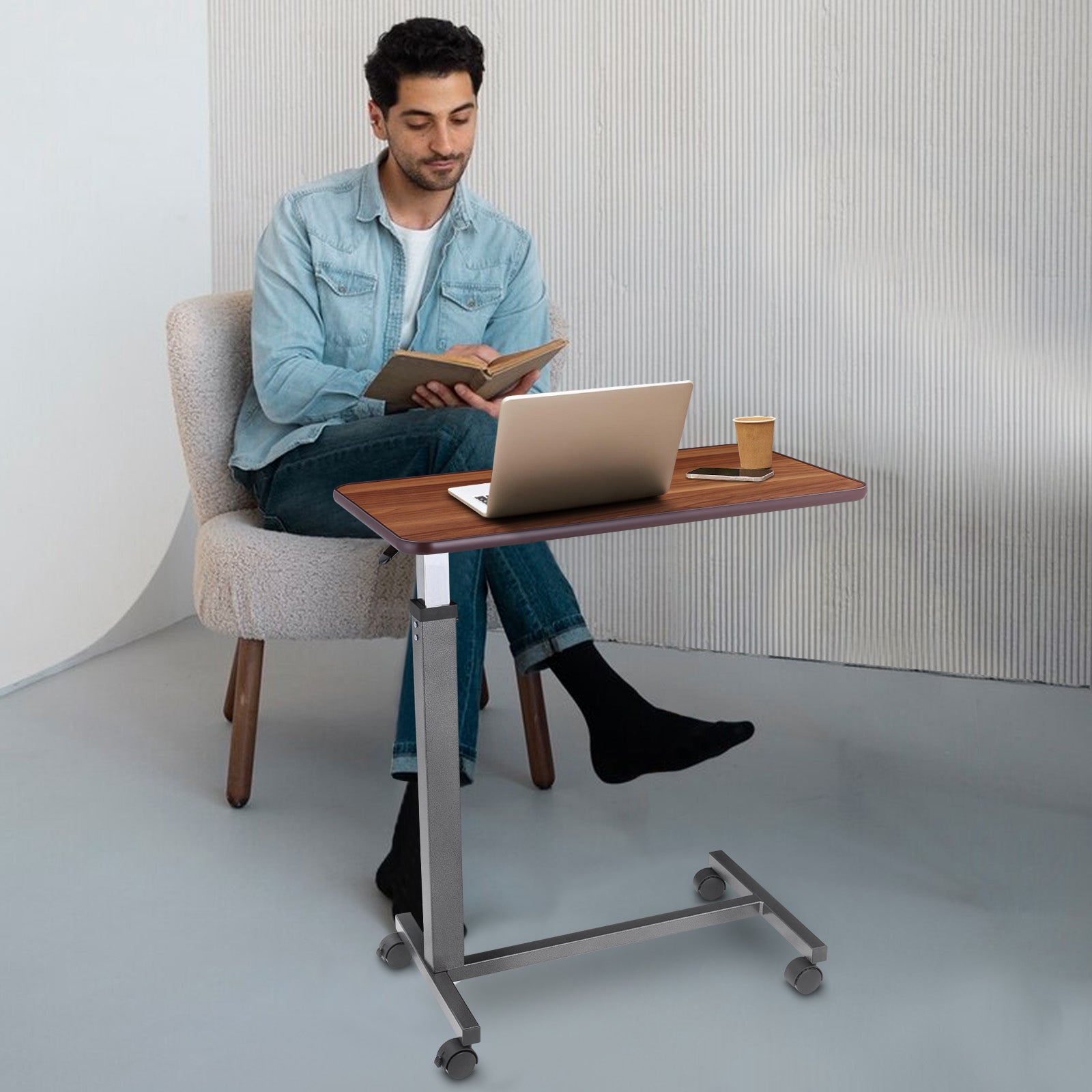 Usage for Work and Study: A young man using the overbed table for reading and working on a laptop, illustrating its versatility in a home office setting.