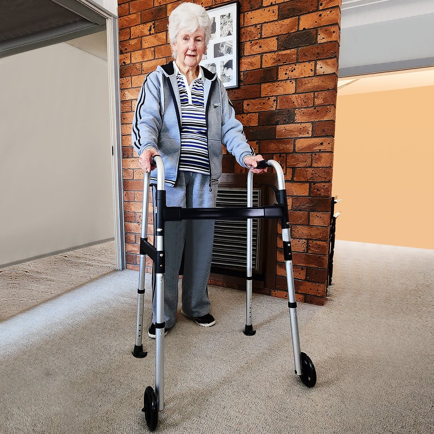 Elderly woman using the Altus Aluminum Folding Walking Frame in a home environment for enhanced mobility