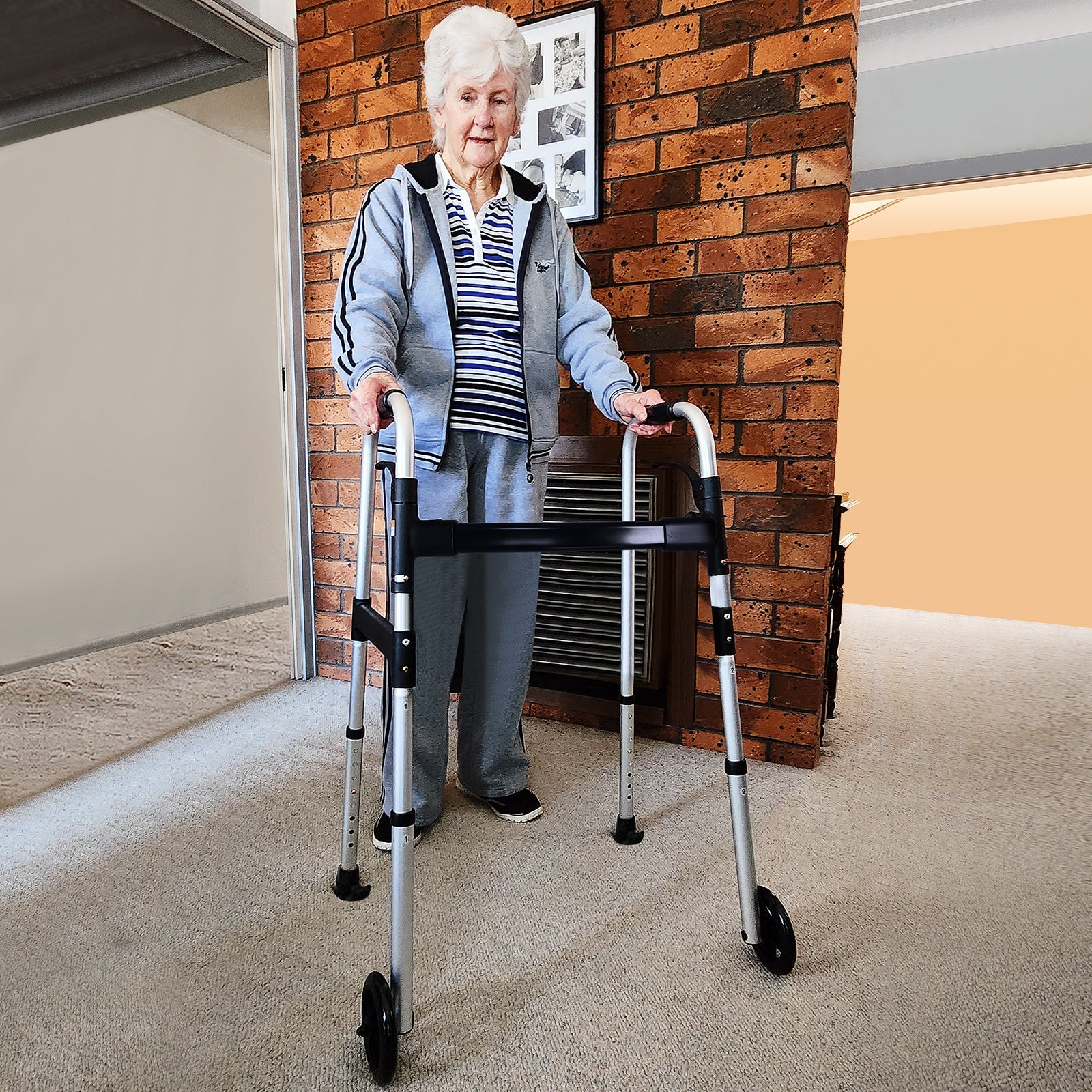 Elderly woman using the Altus Aluminum Folding Walking Frame in a home environment for enhanced mobility