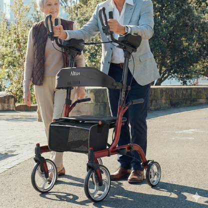 Two people using a red Altus rollator on a street.