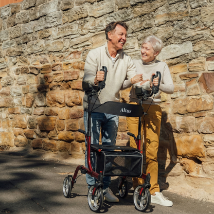 Man and woman using Altus rollators against a stone wall.