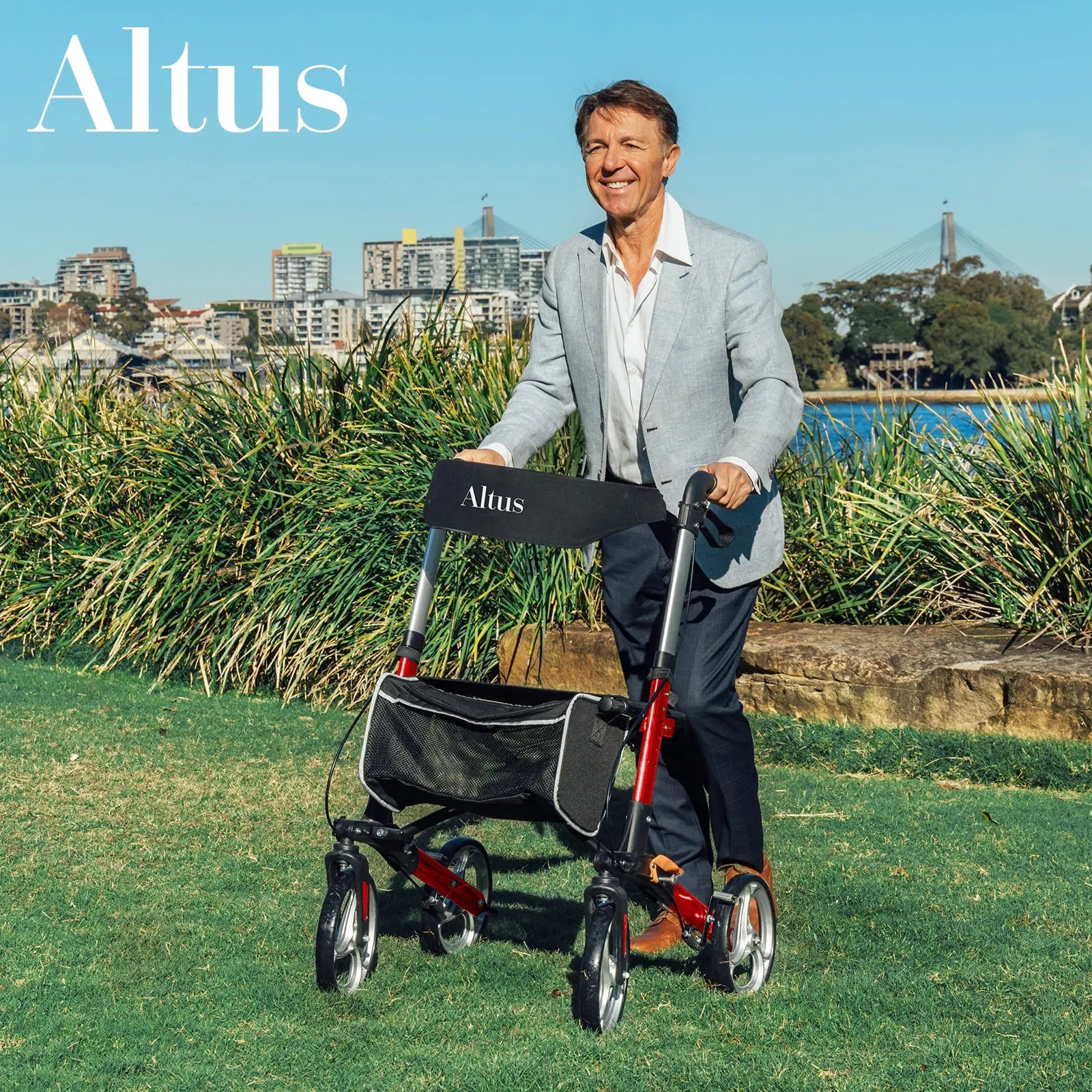 A man is using the Altus Euro Style Rollator in a park, surrounded by greenery. He is dressed in a smart casual outfit, highlighting the rollator's versatility for different occasions. The rollator features large wheels, a comfortable seat, and a spacious storage bag, ensuring stability and practicality. The image underscores the rollator's ability to enhance mobility and provide reliable support for users in outdoor settings.