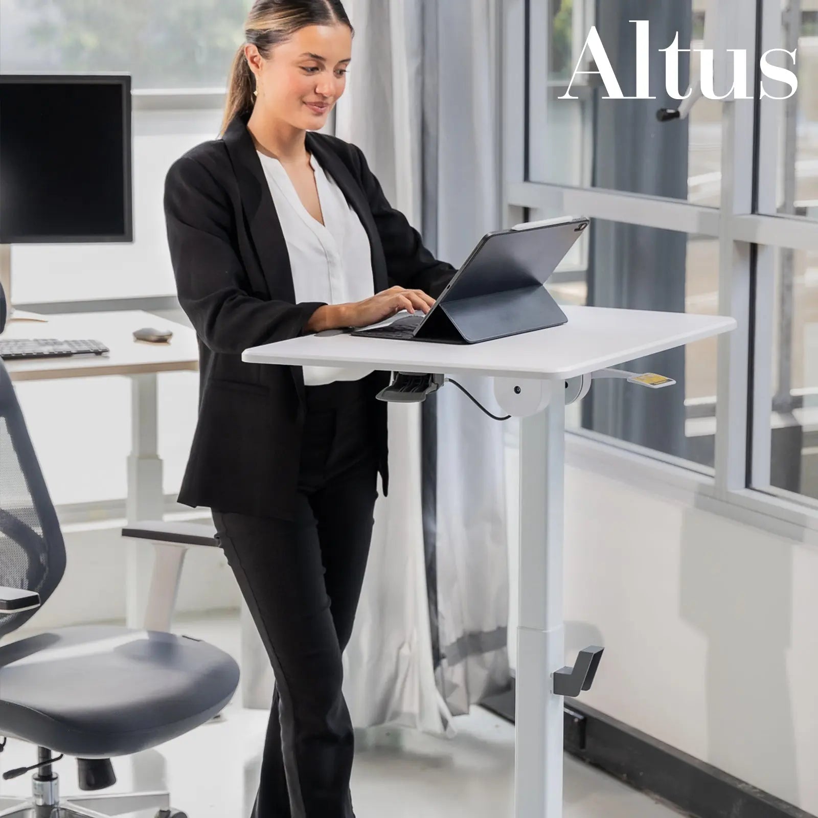 A professional woman using a laptop at a white mobile desk in an active office environment.