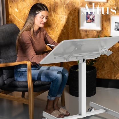 Woman using a laptop on an adjustable standing desk in a modern office setting.