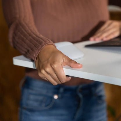 Close-up of a woman's hand adjusting the height of a mobile white desk, demonstrating the desk's adjustability feature.