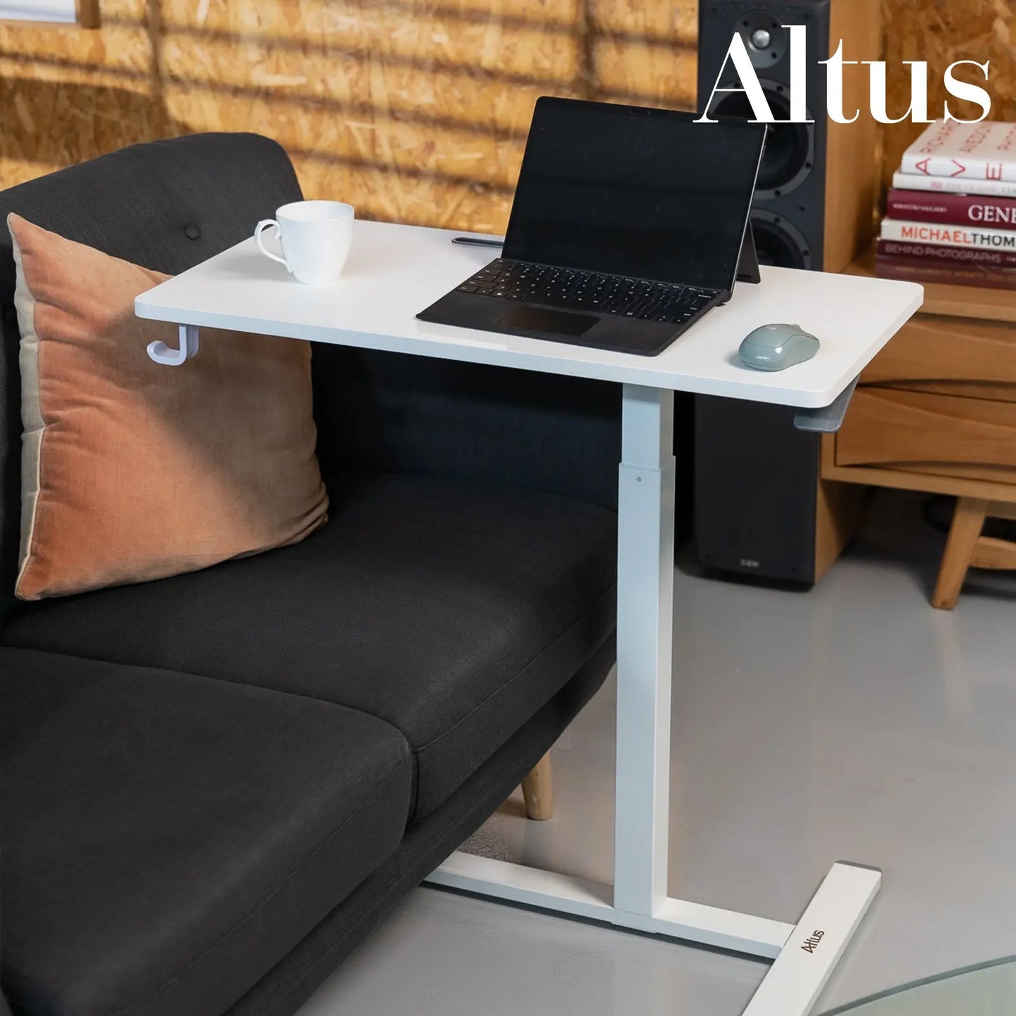 A woman typing on a laptop at a white standing desk in a modern, functional office space with personal decor elements.