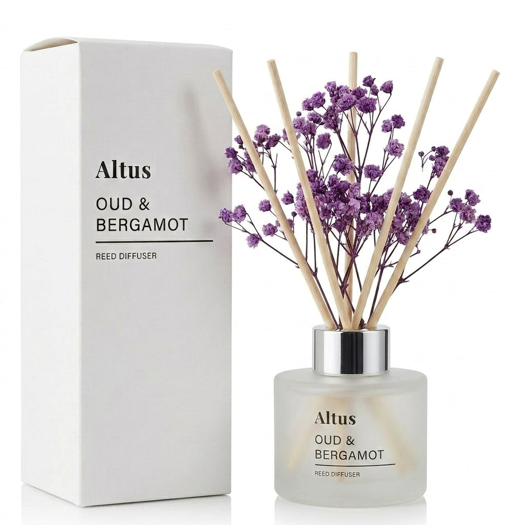 Altus Oud & Bergamot reed diffuser with a frosted glass bottle, purple dried flowers, and natural reed sticks, shown next to its white cardboard packaging box on a white background.