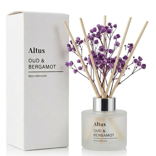 Altus Oud & Bergamot reed diffuser with a frosted glass bottle, purple dried flowers, and natural reed sticks, shown next to its white cardboard packaging box on a white background.