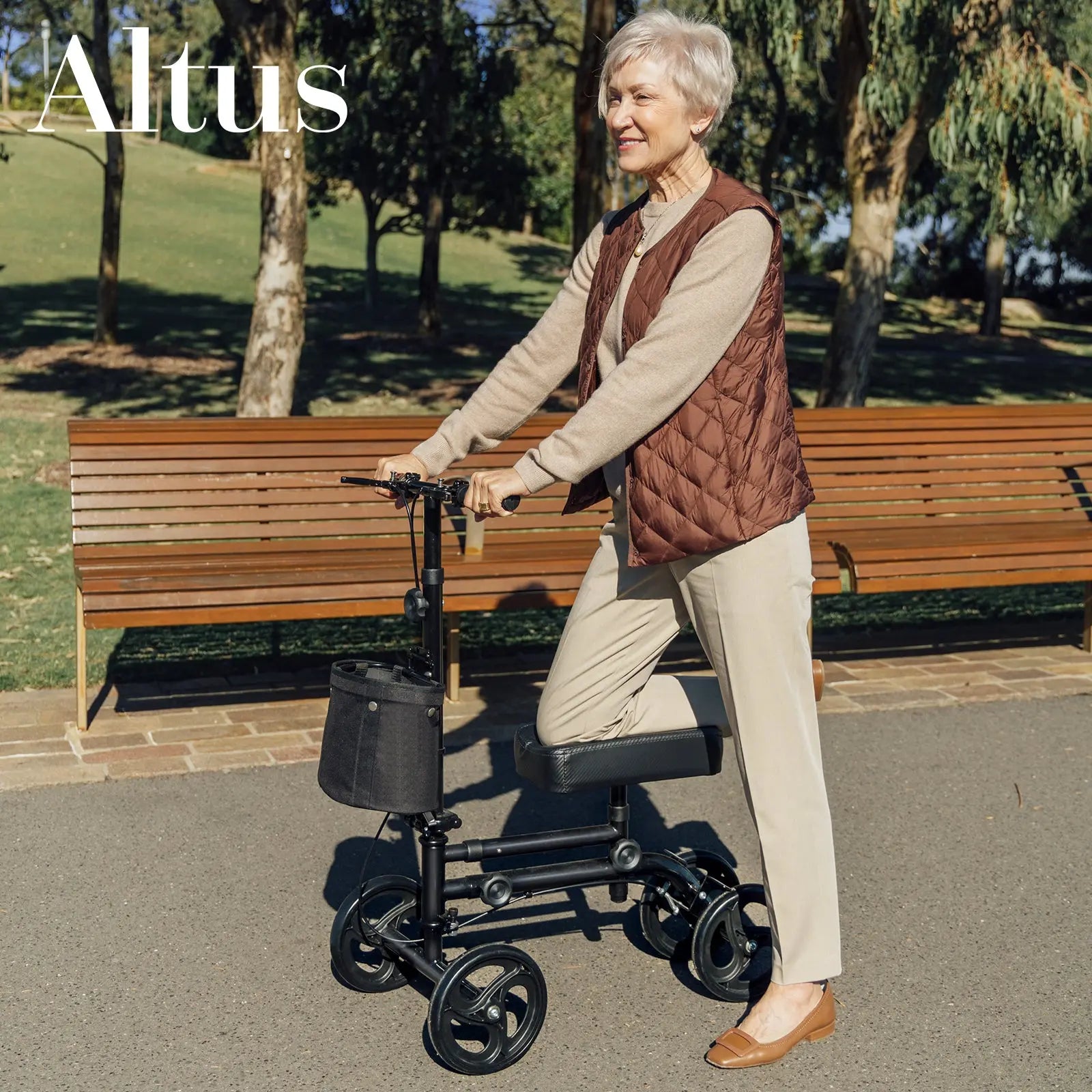 A senior woman using the Altus 8-Inch Wheel Knee Walker Scooter with Cover in a park. The scooter's lightweight design, adjustable handlebars, and spacious storage bag make it ideal for both indoor and outdoor use, enhancing mobility and convenience during recovery.