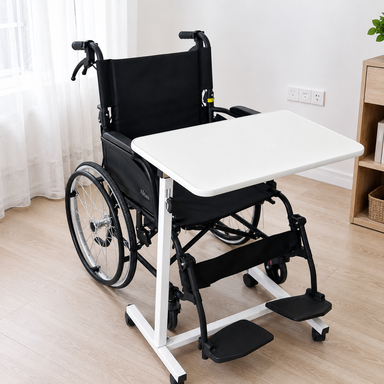 A black manual wheelchair with an attached white rectangular writing desk tray and white support frame, shown in a bright indoor room with light wood flooring and curtains.