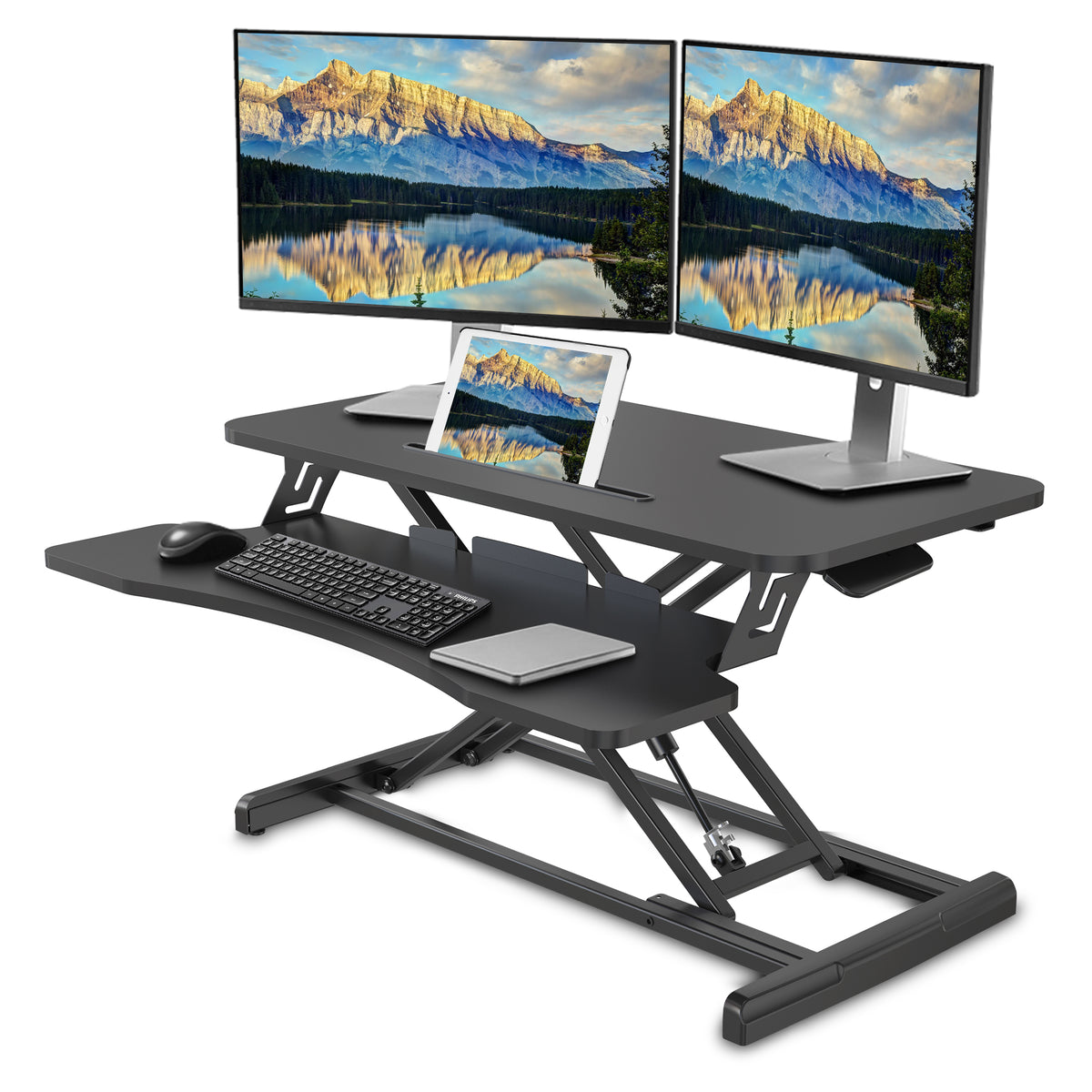 A black adjustable standing desk with dual computer monitors, a tablet, a keyboard, and a mouse, shown on a clean white background.