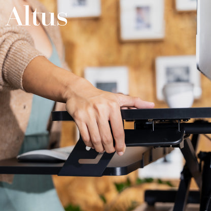 Person using a laptop on an adjustable stand with 'Altus' branding.