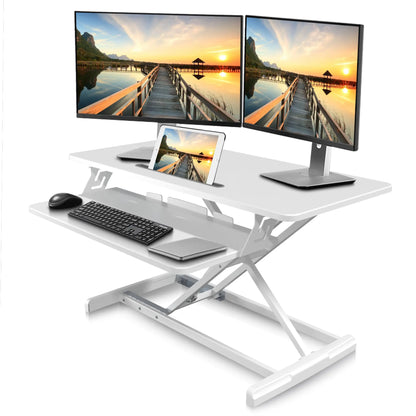 Woman standing at modern ergonomic sit-stand desk riser with dual monitors for healthy workspace setup.