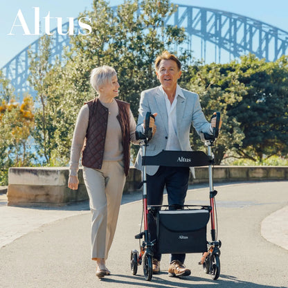 An elderly couple walking near a scenic bridge using the Altus Ergonomic Upright Walker with Seat. Designed for safety and comfort, this walker ensures stability and ease of use for daily activities and outdoor adventures.