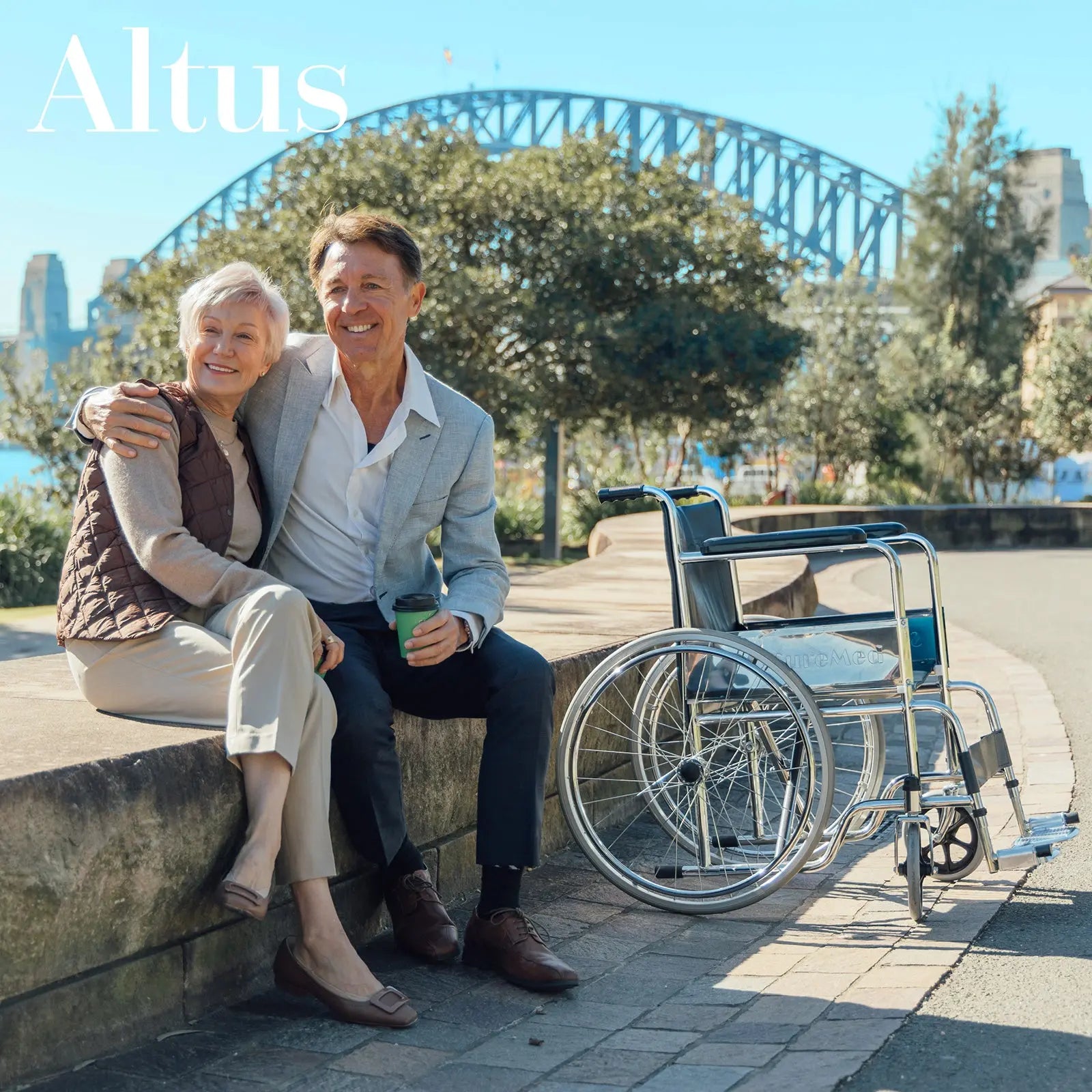 A senior couple sitting on a bench with the Altus Wheelchair with 24-Inch Wheels nearby. This wheelchair's large wheels and ergonomic design ensure smooth maneuverability and comfort, perfect for enhancing mobility and independence.