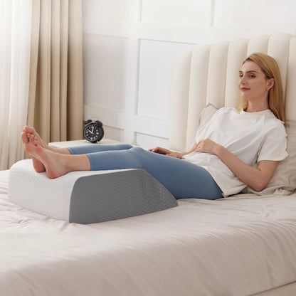 Woman using a wedge pillow on a bed in a bright bedroom.
