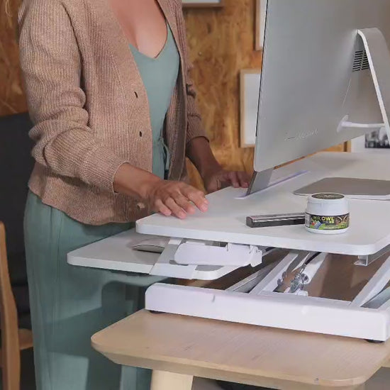 a woman is adjusting a desk to various height levels to accommodate sitting or standing work positions 