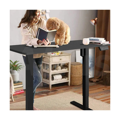 Person using a motorized desk in a cozy home office, interacting with a dog and reading a book.